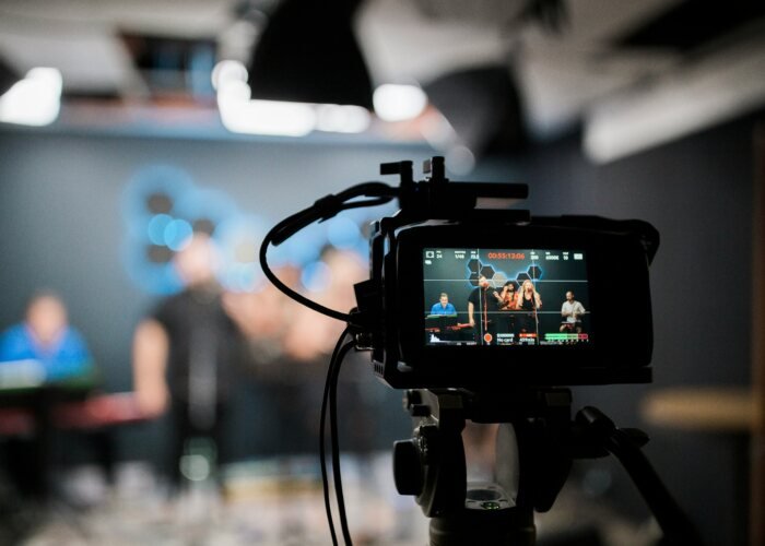 A professional video camera recording a musical group performing in a studio