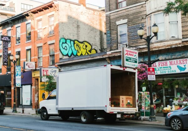 White truck parked on a city street with shops.