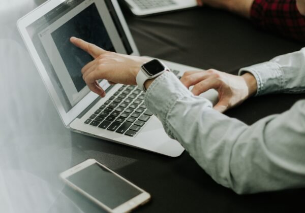 two people sitting at a table with laptops