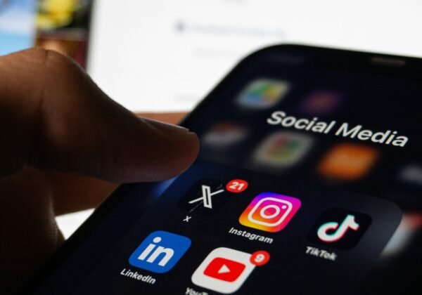 A person holding a smart phone with social media on the screen