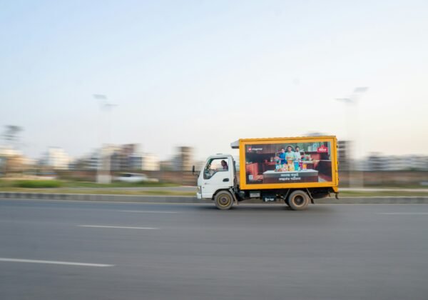 A white truck drives on a road with an advertisement.