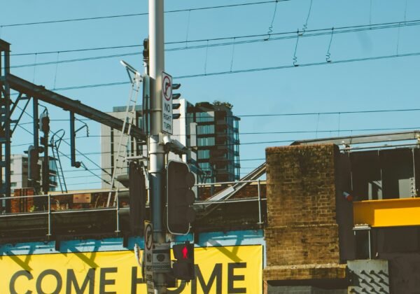 Pedestrians at a city crosswalk with a large ac/dc billboard.